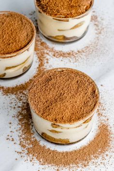 three small desserts with cinnamon sprinkles in them on a white surface