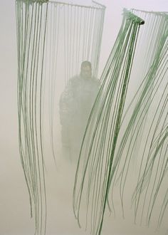 a man is standing in the fog between two large green objects