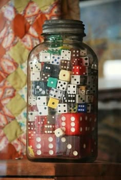 a jar filled with lots of dice on top of a table