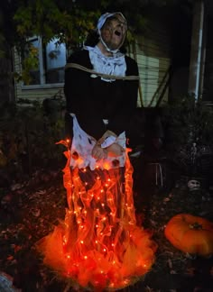 a man dressed as a witch in front of some pumpkins