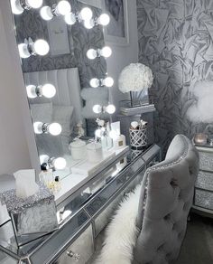 a vanity with a chair, mirror and lights on it in a room filled with furniture