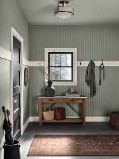 an entryway with green walls and white trim on the wall, wooden bench in between two doors