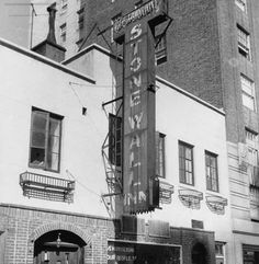 an old black and white photo of a building with a large sign on it's side