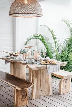 a wooden table with plates and glasses on top of it next to a light fixture