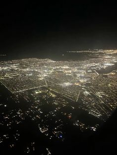 an aerial view of city lights at night from the airplane window, looking down on it