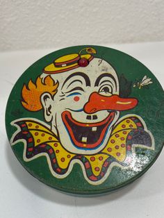 an old tin box with a clown face painted on it