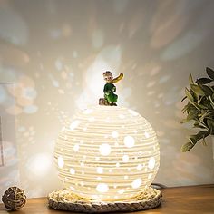 a white lamp sitting on top of a wooden table next to a potted plant