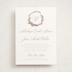 a wedding card with the letter m in gold foil on top of it and an elegant wreath design