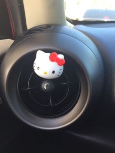 a hello kitty air vent sitting on top of a car steering wheel cover in a vehicle