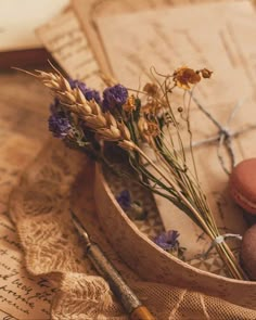 some flowers are in a wooden bowl with macaroons and an old book on the table