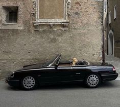 a black convertible car parked on the side of a street next to an old building