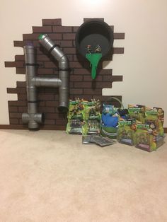 a room with toys and decorations on the floor in front of a brick wall that has a pipe coming out of it