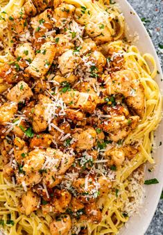 pasta with chicken and parmesan cheese on top in a white plate, ready to be eaten