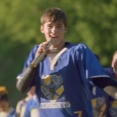 a young man holding a microphone in his right hand and wearing a blue football uniform