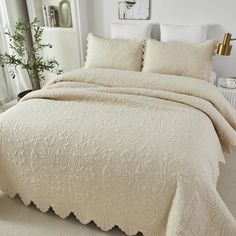 a bed with white linens and pillows in a small room next to a window