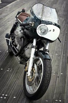 a black and white photo of a motorcycle parked on a wooden deck with the words game over it