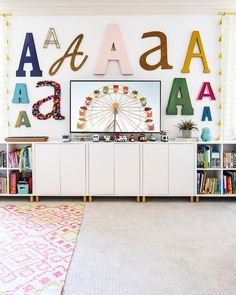 a white entertainment center with letters on the wall and a ferris wheel in the background