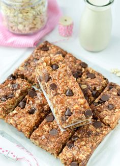 chocolate chip granola bars stacked on top of each other in front of a jar of milk