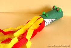 a green and yellow plastic alligator head on top of red and yellow streamers,