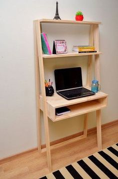 a laptop computer sitting on top of a wooden shelf next to a black and white rug