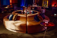 a round couch with candles on it in the middle of a room filled with tables and chairs