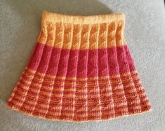 an orange and pink knitted skirt laying on the floor