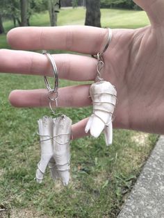 a hand holding two pairs of white earrings