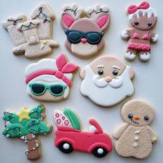 some decorated cookies are sitting on a white counter top and one is wearing sunglasses, the other has a santa clause