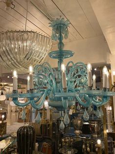 a blue chandelier hanging from the ceiling in a room filled with glass items