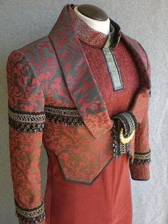 a mannequin wearing a red dress with gold trimmings and an elaborate collar