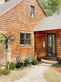 a wooden house with two lawn chairs in front of it