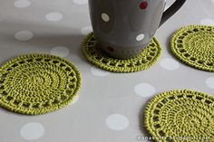 four crocheted coasters on a table with polka dotty cloth and coffee cup