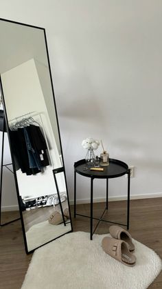 a large mirror sitting on top of a wooden floor next to a small black table