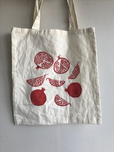 a tote bag with pomegranates on it hanging from the wall