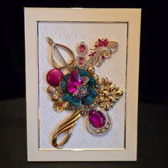 a white frame holding a bunch of different types of jewelry in it's center