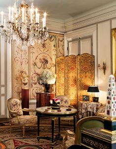 a living room filled with furniture and a chandelier hanging from the ceiling over a table