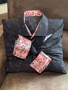 a black shirt with red and white designs on it is sitting on a brown couch