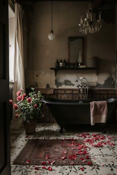 a bathtub with rose petals on the floor in a bathroom next to a chandelier