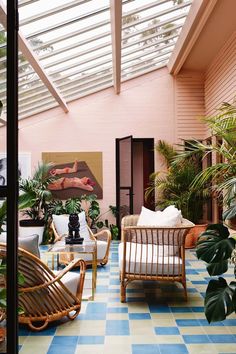 a living room filled with furniture and lots of plants on top of the floor next to a skylight