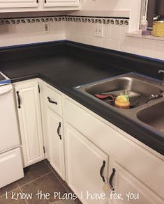 a kitchen with white cabinets and black counter tops is pictured in this image, the sink has an empty dishwasher next to it