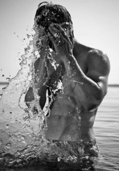 a shirtless man splashing water on his face