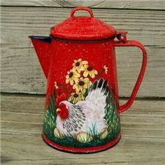 a red ceramic coffee pot with a rooster painted on the side and flowers in the background