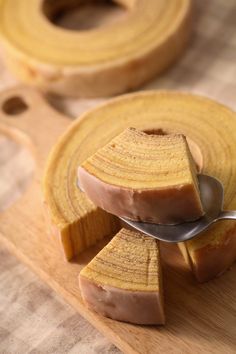 a wooden cutting board with slices of cake on it and a spoon in the middle