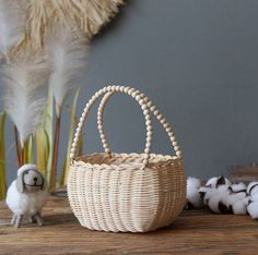 a small white basket sitting on top of a wooden table next to cotton floss