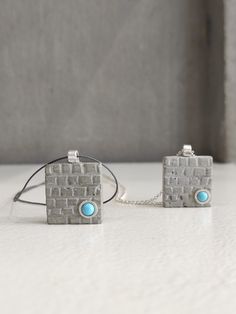 "This pendant necklace is handcrafted & made of gray concrete whose surface looks like a wall. It  is decorated at the bottom with a tiny turquoise (synthetic) stone, which is tied with sterling silver and so is the link. The pendant is strung on a silver chain or a gray cord with handmade hooks. You can choose one of the two according to your taste! It's an unusual piece of jewelry that you can enjoy wearing every day! In contact with skin, moisture and air, concrete becomes darker. Αs each piece is individually handmade, slight variations in  texture are possible. DESCRIPTIONS and MEASUREMENTS: Material: Sterling silver . Material: Concrete Stone:Round synthetic turquoise. Cord: Grey synthetic cord & Silver chain. Dimensions: 2,0x1,8 (cm) 0,78x0,71 (in)\" thickness: 0,40 (cm) 0,16 (in)\" Concrete Necklace, Grey Necklace, Square Pendant Necklace, Gray Concrete, Gray Necklace, Concrete Stone, Square Rings, Square Pendant, Geometric Pendant