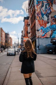 a woman is walking down the street in thigh high boots