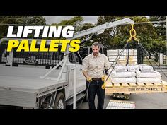 a man standing next to a truck with pallets on it