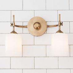 three lights are on the wall in front of a white brick wall and tile floor