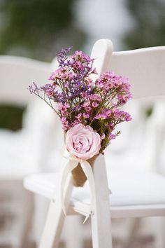 a bouquet of pink flowers sitting on top of a white chair with ribbon tied around it