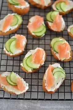 several pieces of bread with salmon and cucumber on them sitting on a cooling rack